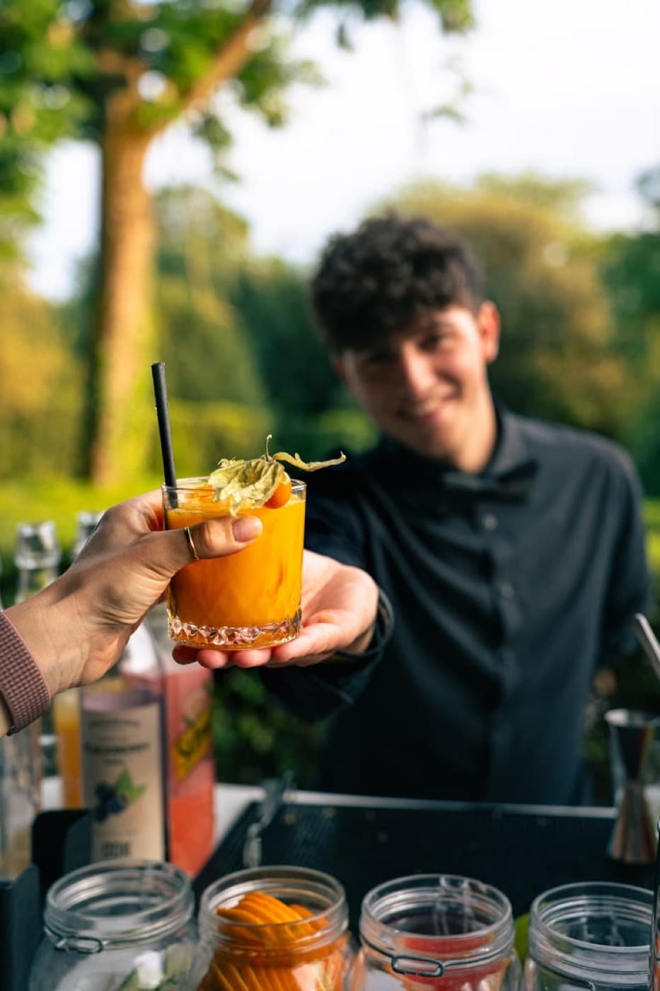 Bartender de RUTABAR sirviendo un cóctel con guarnición de fruta a un invitado durante un evento